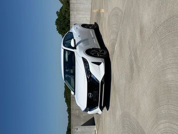 White sedan parked on a rooftop under clear blue skies.