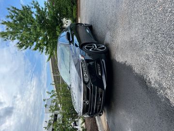Black Honda sedan parked on a paved surface under a cloudy sky.