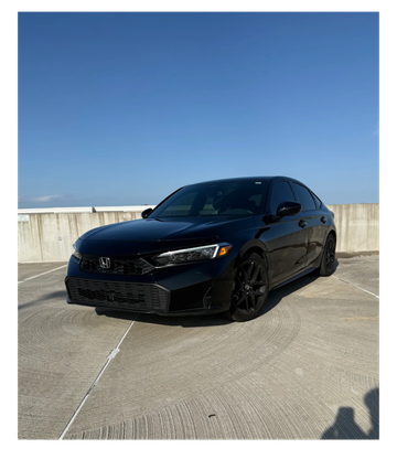 Sleek black Honda sedan parked under clear blue sky on concrete surface.