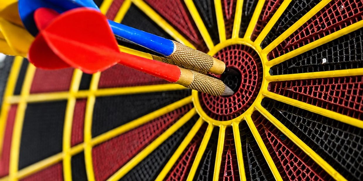 Two darts hit the bullseye on a dartboard.