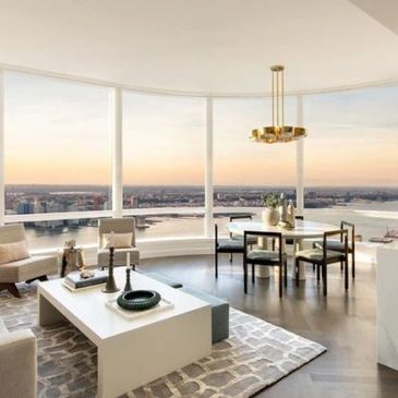 Luxurious modern living room with panoramic city and river views through floor-to-ceiling windows.