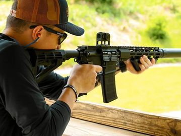 Person aiming a rifle at a shooting range.