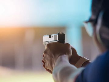 Person aiming a handgun at a shooting range.