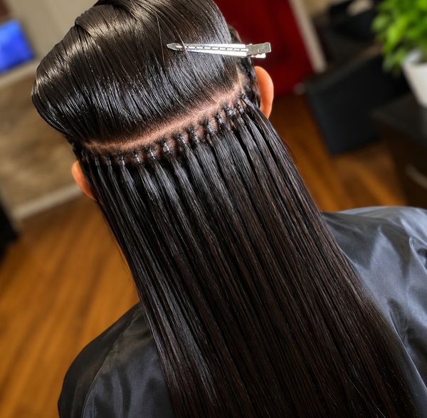 Close-up of hair extensions being applied with neat, tiny sections.