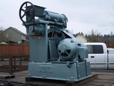 Industrial machine with large flywheel outdoors.