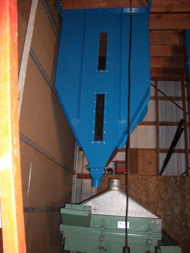 Industrial blue hopper and machinery inside a wooden structure.