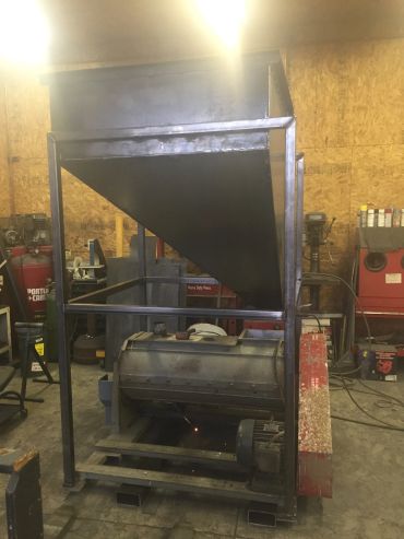 Industrial metal hopper and machinery in workshop.