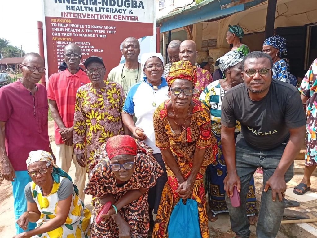 Group of elderly people and a man gathered in front of a health literacy center.