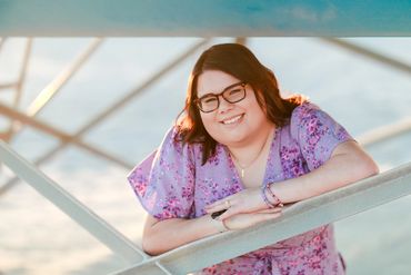 Woman smiling outdoors, leaning on a railing.