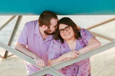 Couple sharing a tender moment under a structure.