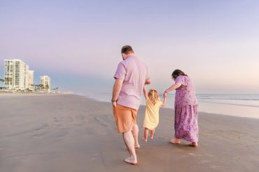 Family walking on the beach at sunset.