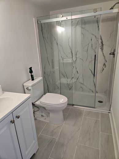 Modern bathroom with glass shower and marble tiles.