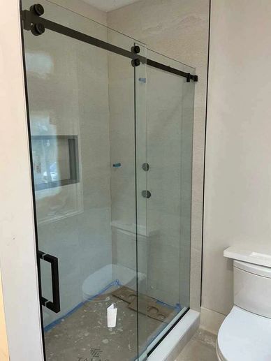 Modern bathroom with glass shower enclosure and white toilet.