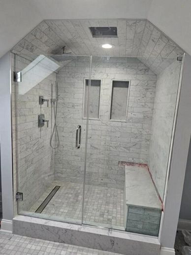 Modern walk-in shower with glass doors and marble tiles.