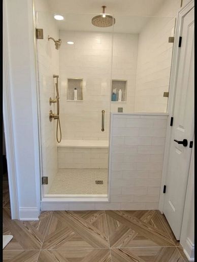 Modern walk-in shower with glass door and wood-patterned tile floor.