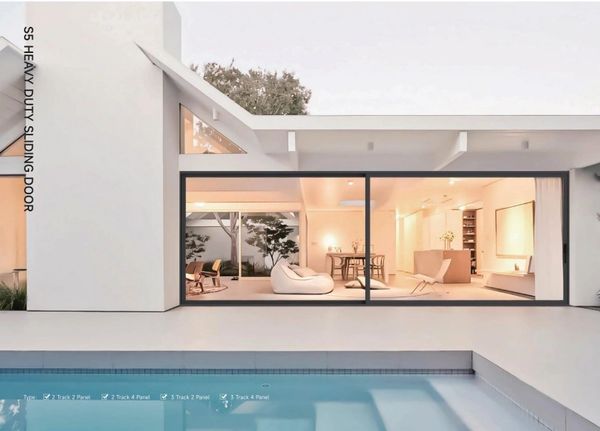 Modern house with large sliding glass doors opening to a pool area.