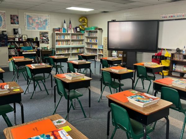 Empty classroom with desks and books organized.