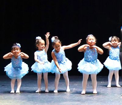 Young girls performing ballet in blue tutus on stage.