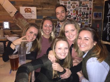Group of five friends smiling at a bar.