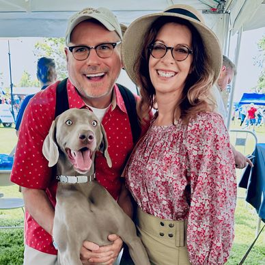 Paul, his wife, and their Weimaraner share a smile at a local community gathering.