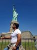 Person posing near the Statue of Liberty.