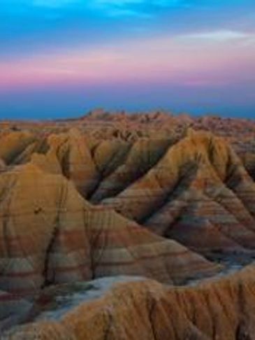 Colorful layered rock formations under a vibrant sky.