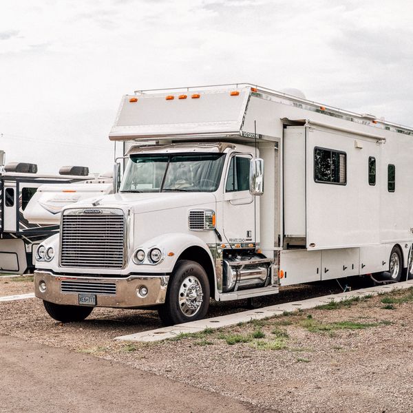 Large white motorhome truck parked on gravel.
