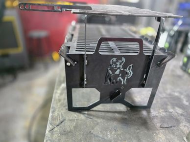 Black metal grill with a bull design on the front, sitting on a table.