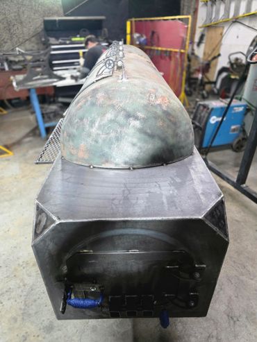Industrial metal furnace or smoker in a workshop setting.