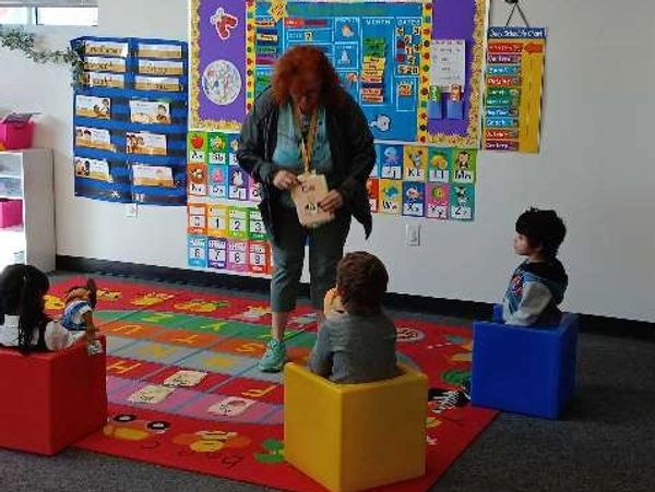 Teacher interacting with preschool kids in colorful classroom.