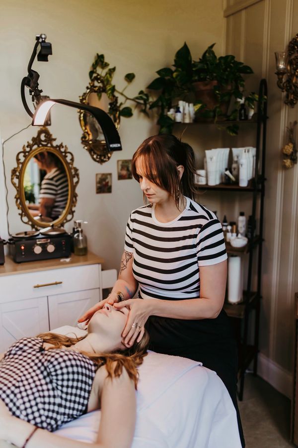 A therapist provides a facial massage to a client in a cozy treatment room.