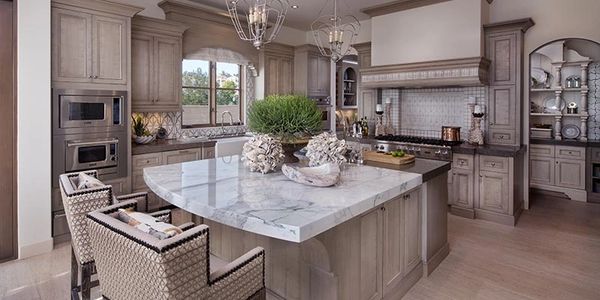 calacatta porcelain counter top with tan custom cabinetry and stylish hood cover and double oven unit 