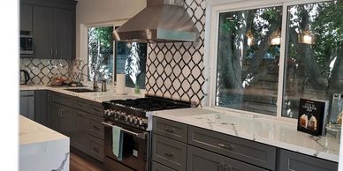 Grey semi custom shaker cabinets with marble look countet top and free standing hood in west hills