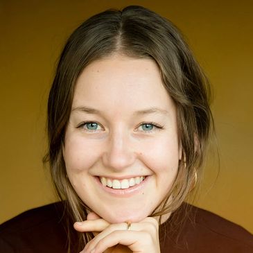 Smiling young woman with hand near chin.