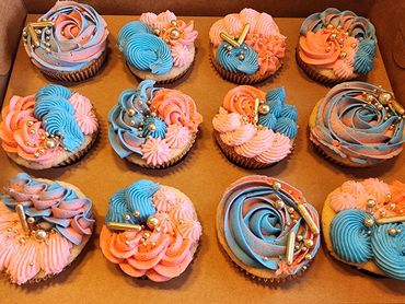 Colorful cupcakes decorated with blue, pink, and peach swirled frosting and gold sprinkles.