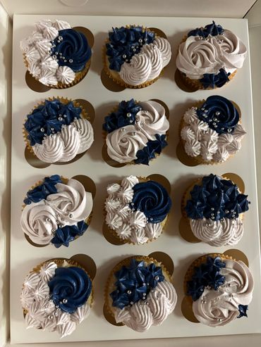 Box of twelve elegant cupcakes with blue, white, and silver decorations.