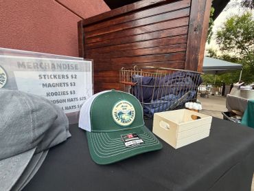 A green and white cap displayed on a table with a merchandise price list.