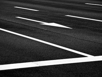Black asphalt with white road markings and a directional arrow.