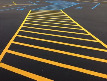 Freshly painted yellow pedestrian crossing lines on dark asphalt.