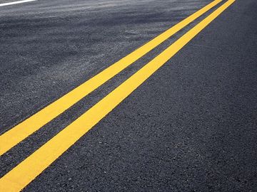 Freshly painted double yellow lines on a smooth asphalt road.