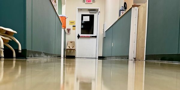 Empty hallway with a white exit door and reflective floor.