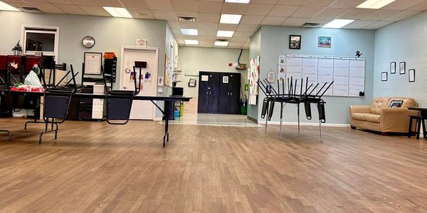 A clean, organized classroom with chairs stacked on tables and a whiteboard on the wall.