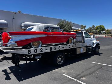 Classic red car on a flatbed tow truck.