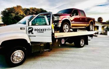 Tow truck carrying a red pickup truck.