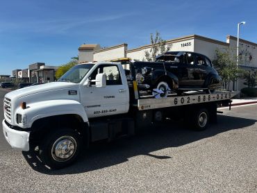 Tow truck carries a vintage black car.