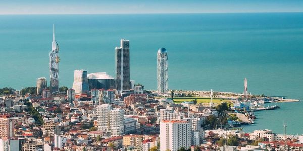 A coastal cityscape with modern buildings and a clear blue sea under a bright sky.