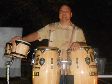 Man playing conga drums at night.