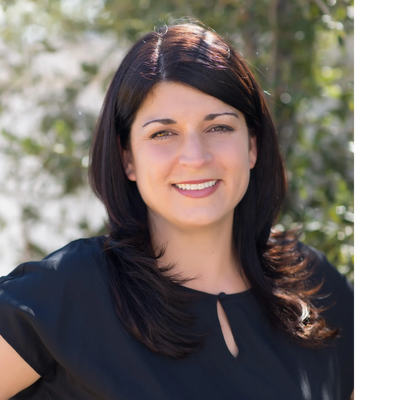 Smiling woman with dark hair wearing a black blouse outdoors.