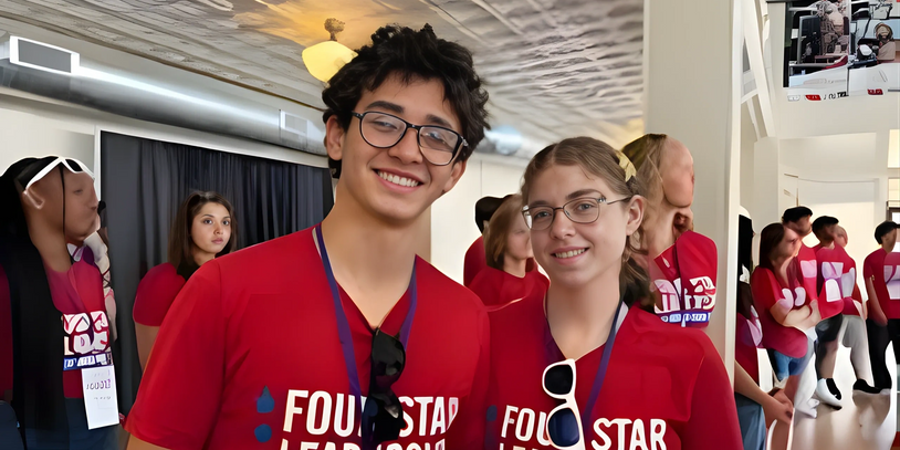 Two young people in red "Four Star Leadership" shirts smiling indoors.