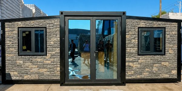 Modern tiny house with stone facade and large glass doors.